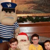 Three boys sitting with Santa & Louie.